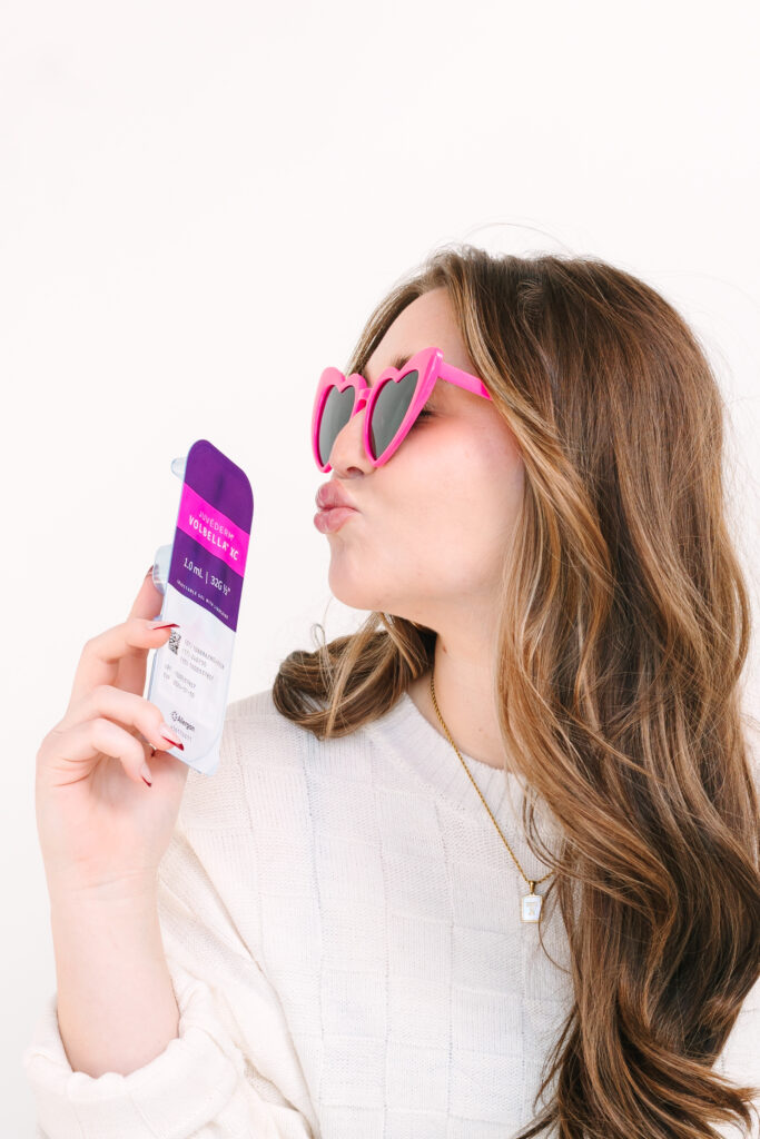 woman in pink sunglasses holding juvederm